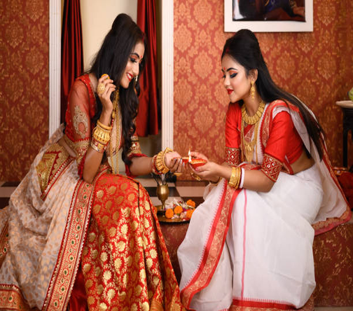 Bengali women in traditional red and white sarees celebrating Poila Baisakh with rituals and festive sweets