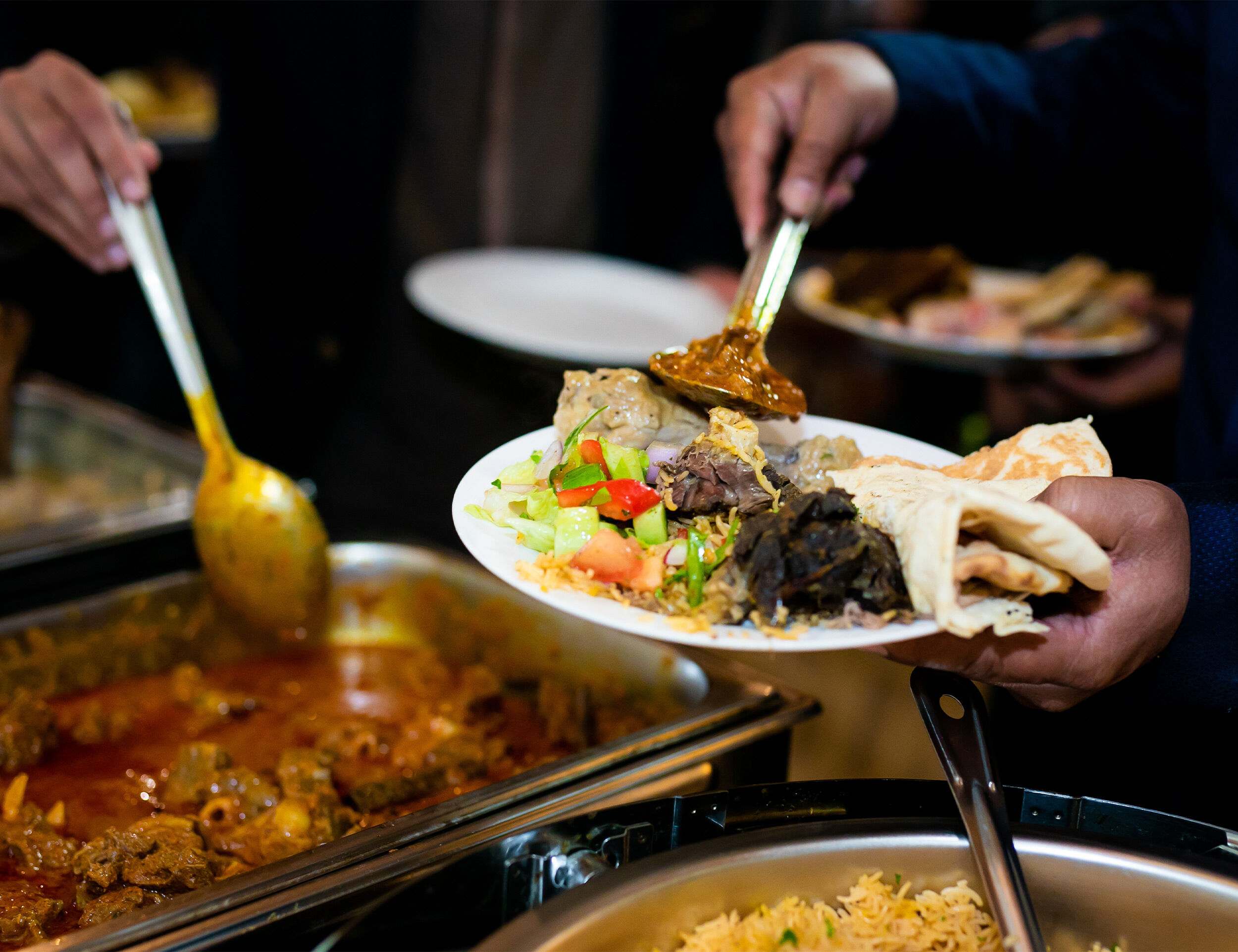 A man filling his plate with Wedding food for Indian weddings