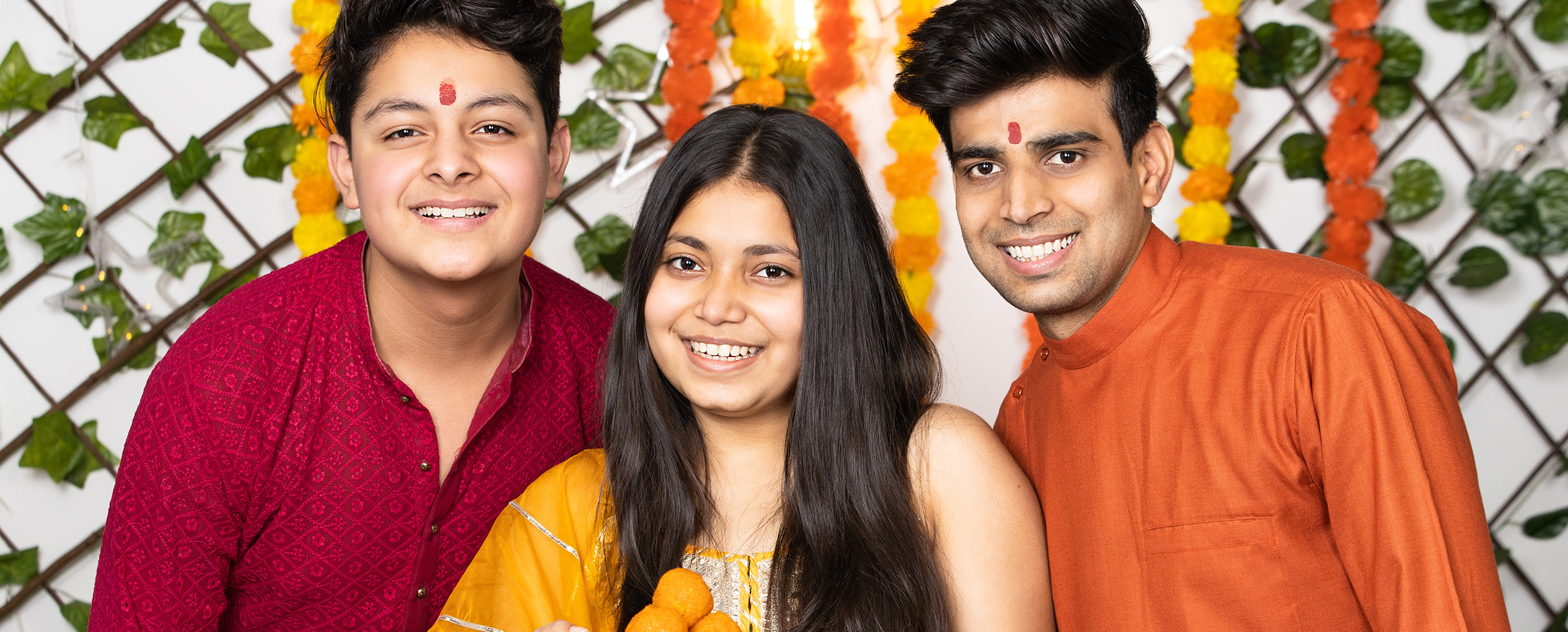 Siblings celebrating the festive occasion of Bhai Dooj, proudly holding a plate of traditional Ladoos.