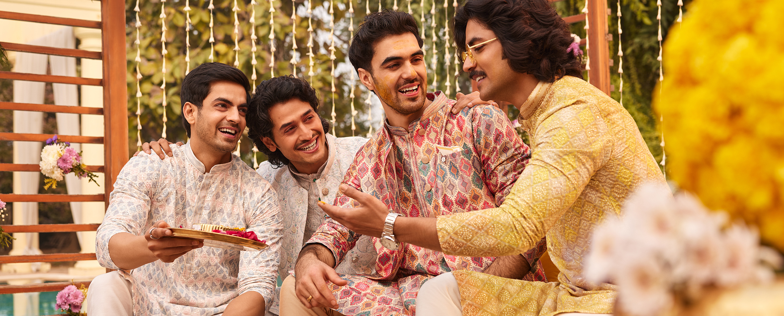 Group of men in colorful modern Indian ethnic wear laughing and celebrating at a wedding event Group of men in colorful modern Indian ethnic wear laughing and celebrating at a wedding event