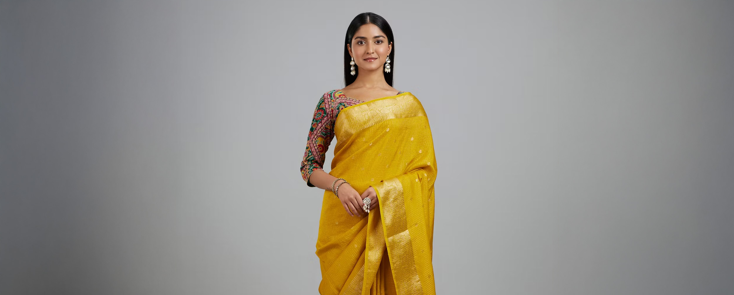 Indian woman in a heavily embroidered teal and silver lehenga with matching jewelry and headpiece.