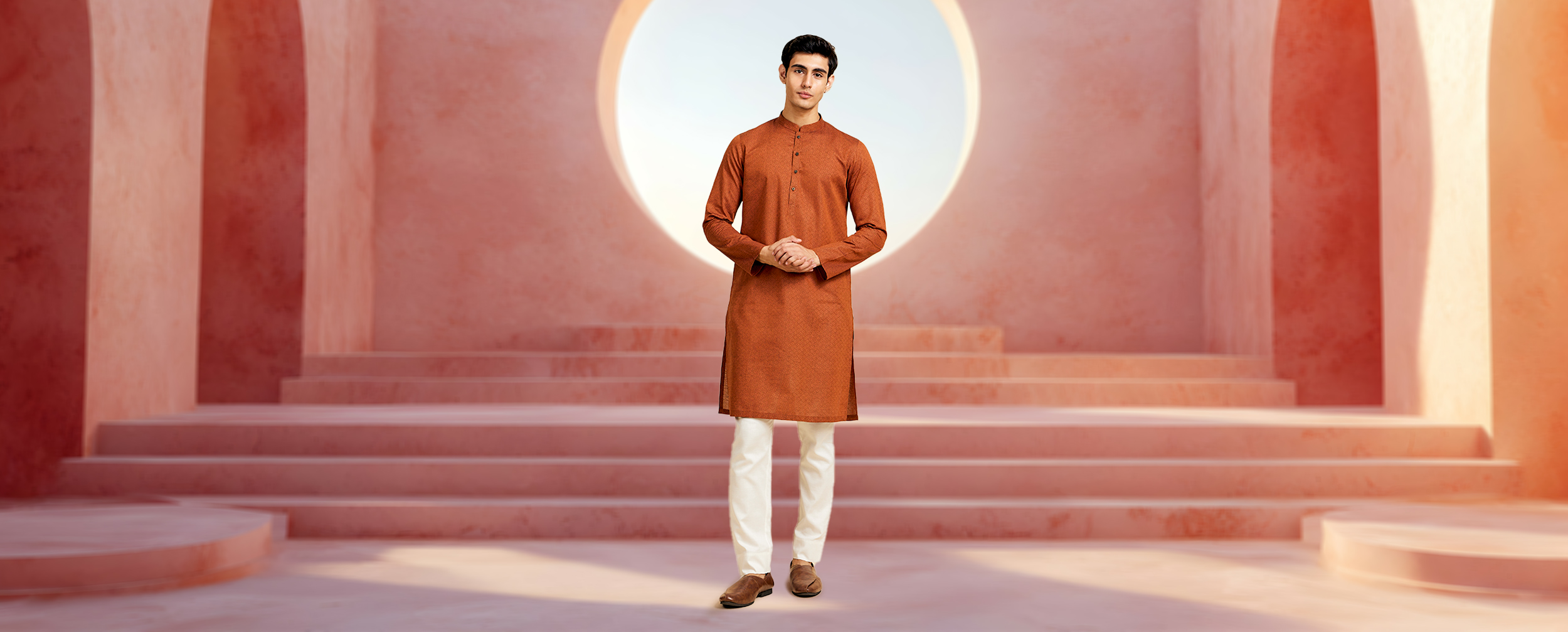 Man wearing a rust orange kurta with off-white churidar, styled for Eid celebrations with a clean and festive look.