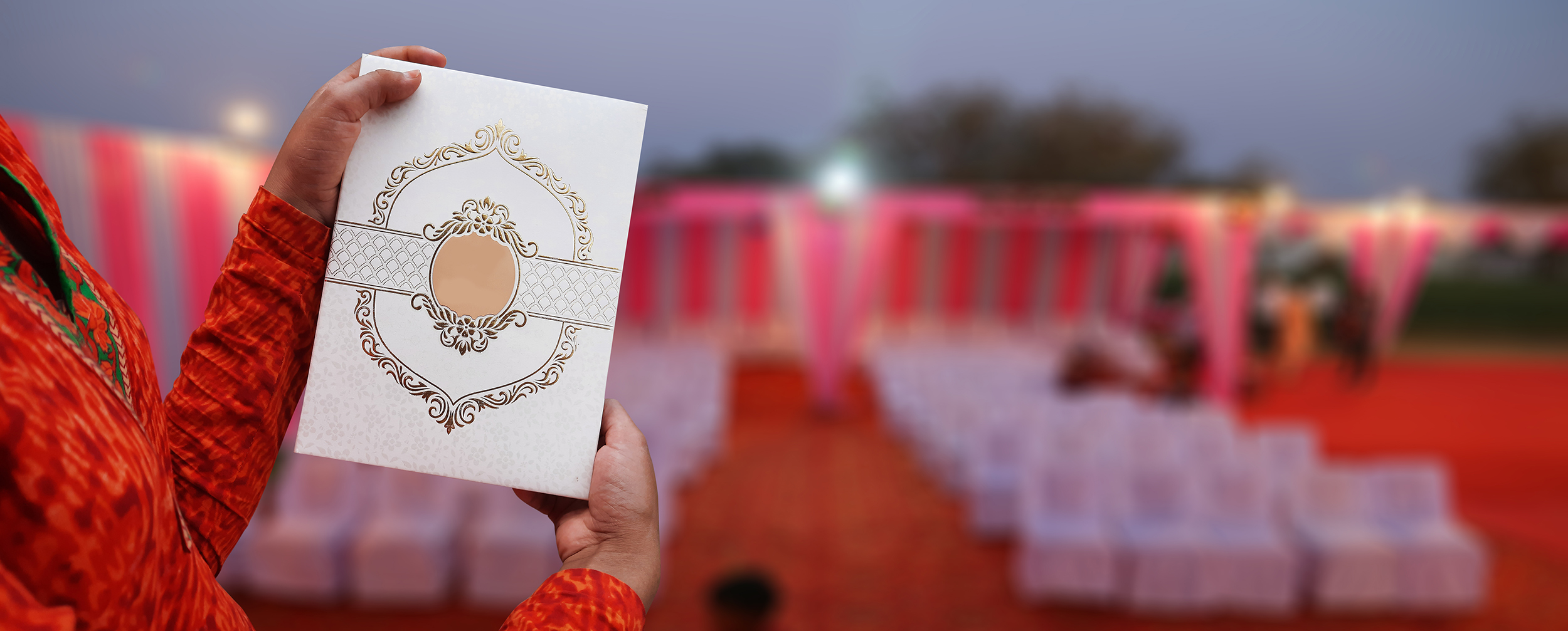 A man holding a beautiful creative white colour designed wedding card.