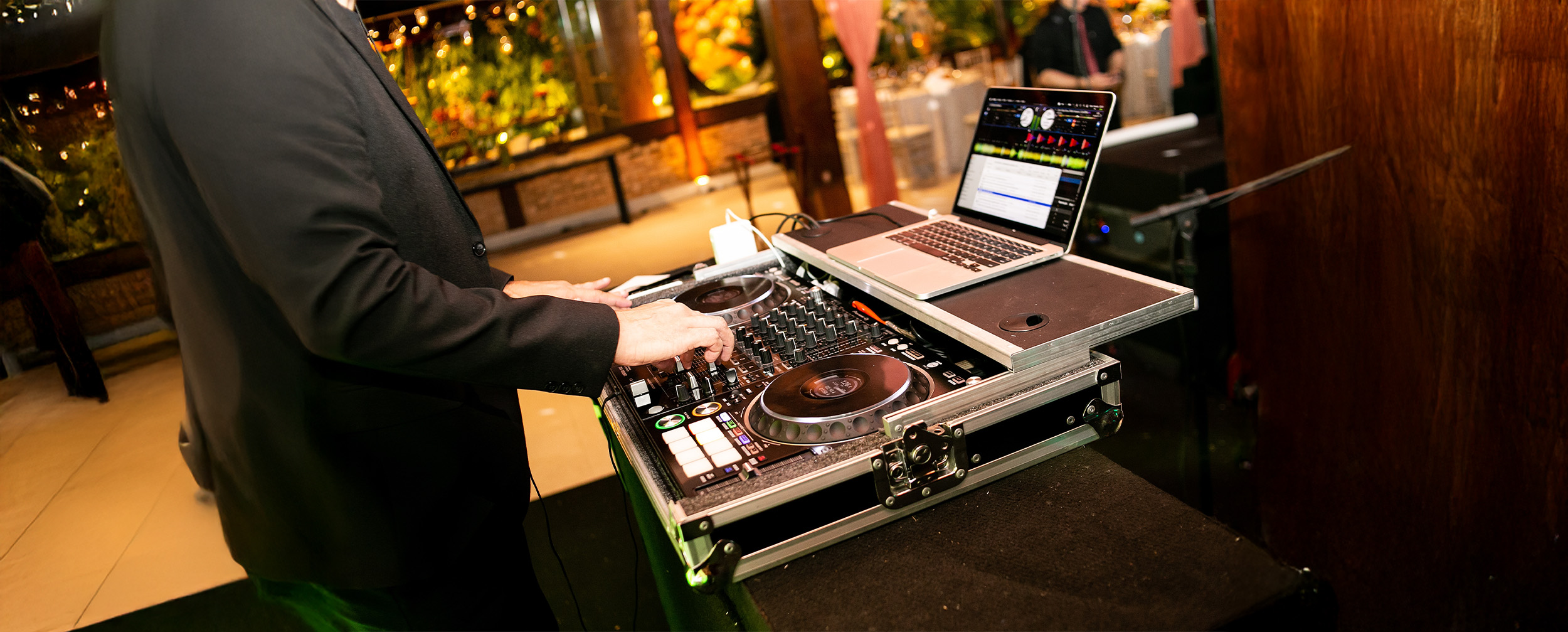Young DJ operating music console at a Mehendi function playing festive playlist