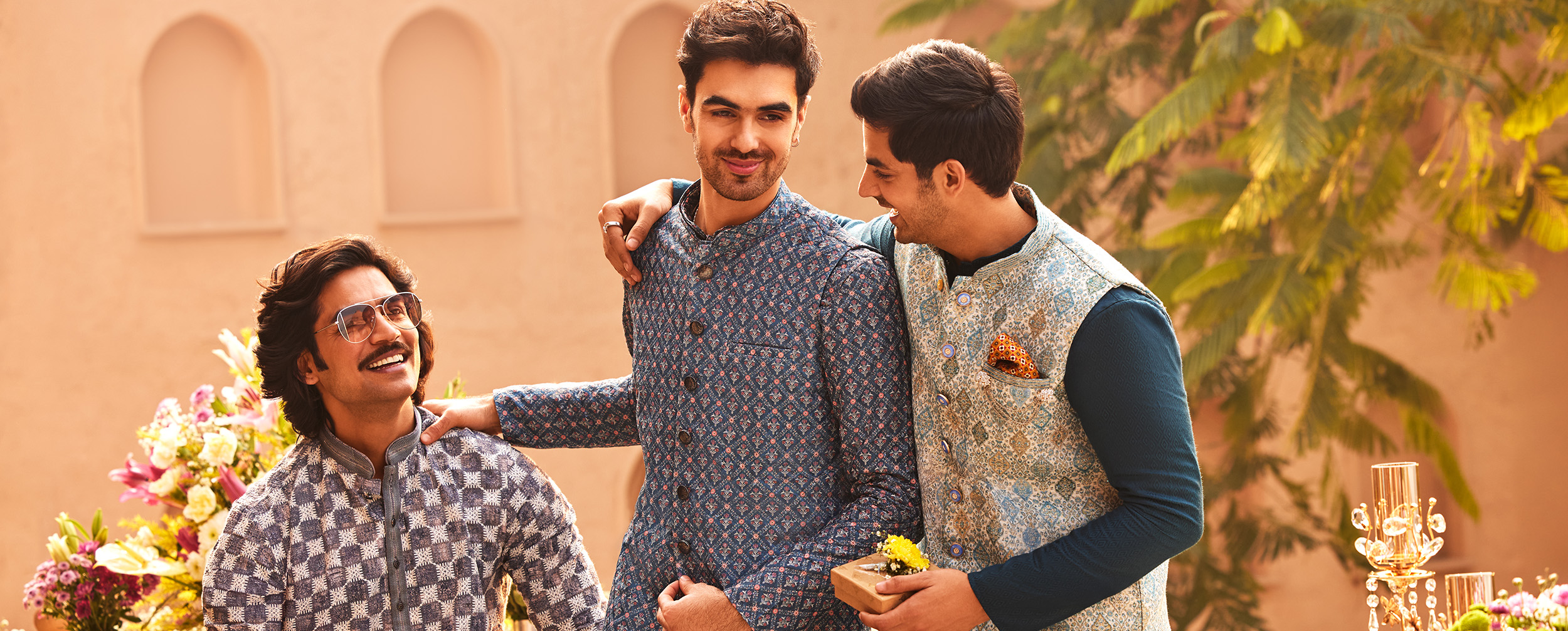 Three men in printed kurtas and bandi jackets, showcasing colorful festive men's wear.  Three men in printed kurtas and bandi jackets, showcasing colorful festive men's wear.