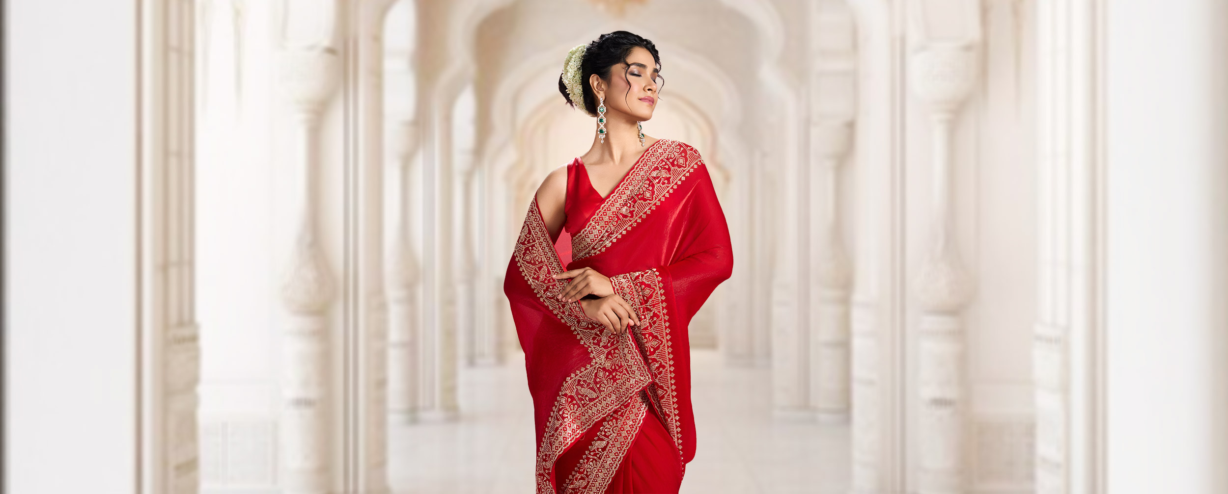 Woman wearing a red saree with intricate gold embroidery, styled for a festive Navratri or Garba celebration.