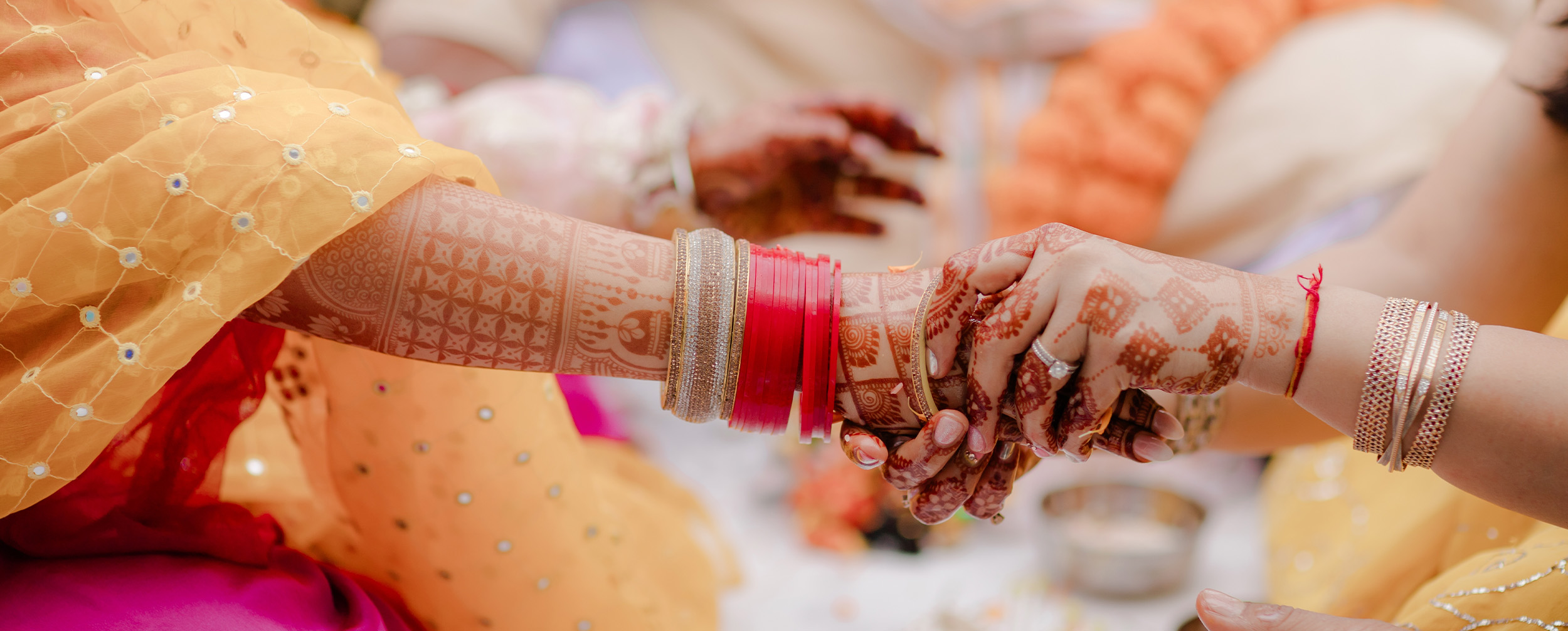 Close-up of bride’s hands adorned with red chooda bangles and intricate mehndi designs during a traditional Punjabi chuda ceremony Close-up of bride’s hands adorned with red chooda bangles and intricate mehndi designs during a traditional Punjabi chuda ceremony