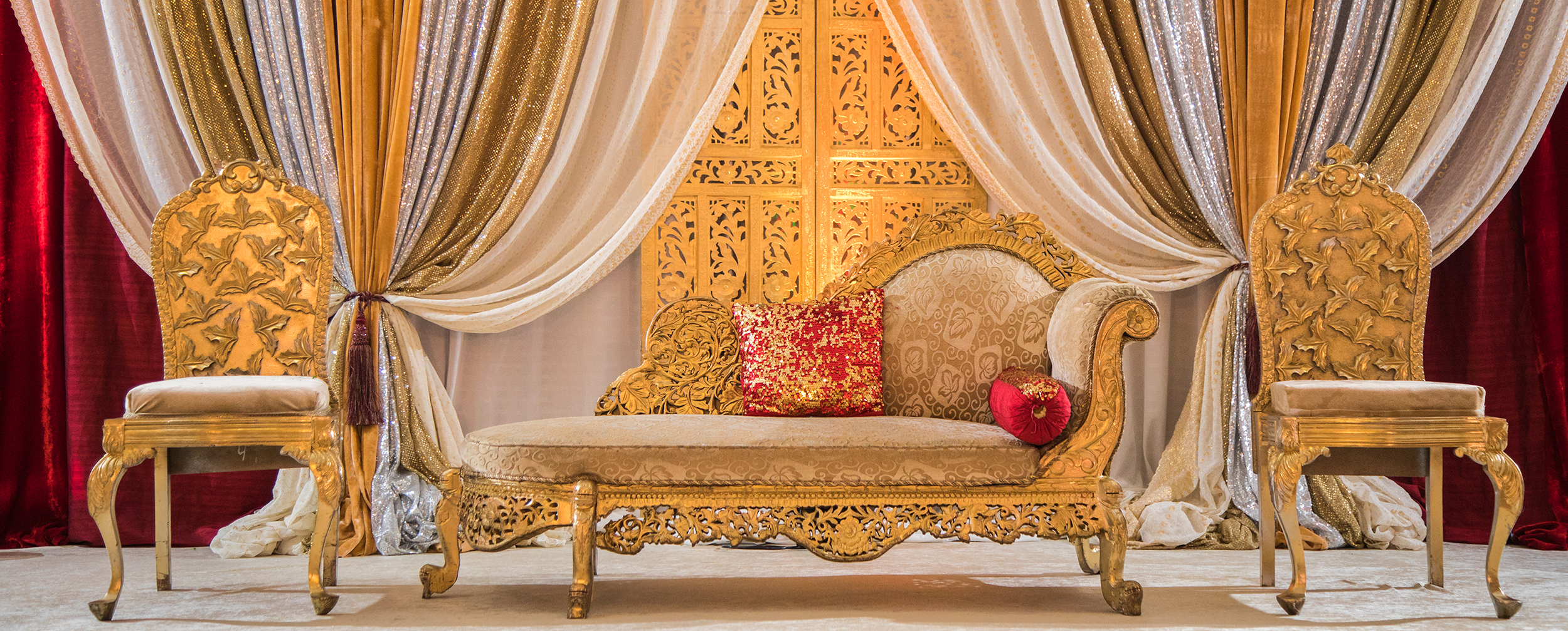 Luxurious South Indian wedding stage decor with golden sofa, rich drapes in gold and silver, and ornate backdrop for traditional celebration. Luxurious South Indian wedding stage decor with golden sofa, rich drapes in gold and silver, and ornate backdrop for traditional celebration.
