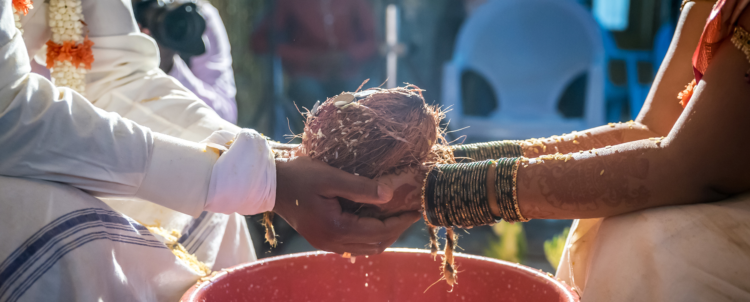 Close-up of a South Indian wedding ritual in Karnataka, with a bride and groom holding a coconut over a red vessel, symbolizing traditional Kannada marriage customs. Close-up of a South Indian wedding ritual in Karnataka, with a bride and groom holding a coconut over a red vessel, symbolizing traditional Kannada marriage customs.