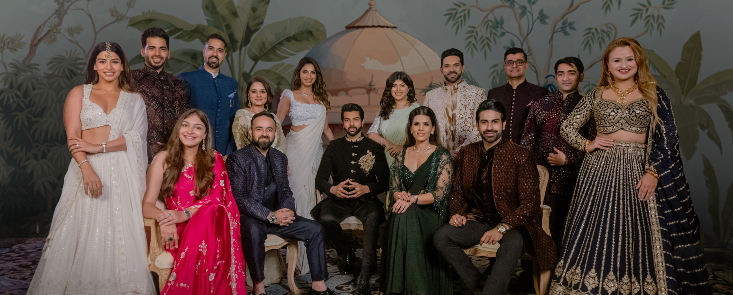 Group of men and women dressed in elegant Indian ethnic wear including lehengas, sarees, and sherwanis, posing together indoors for the Manyavar Wedding Ambassador Program.