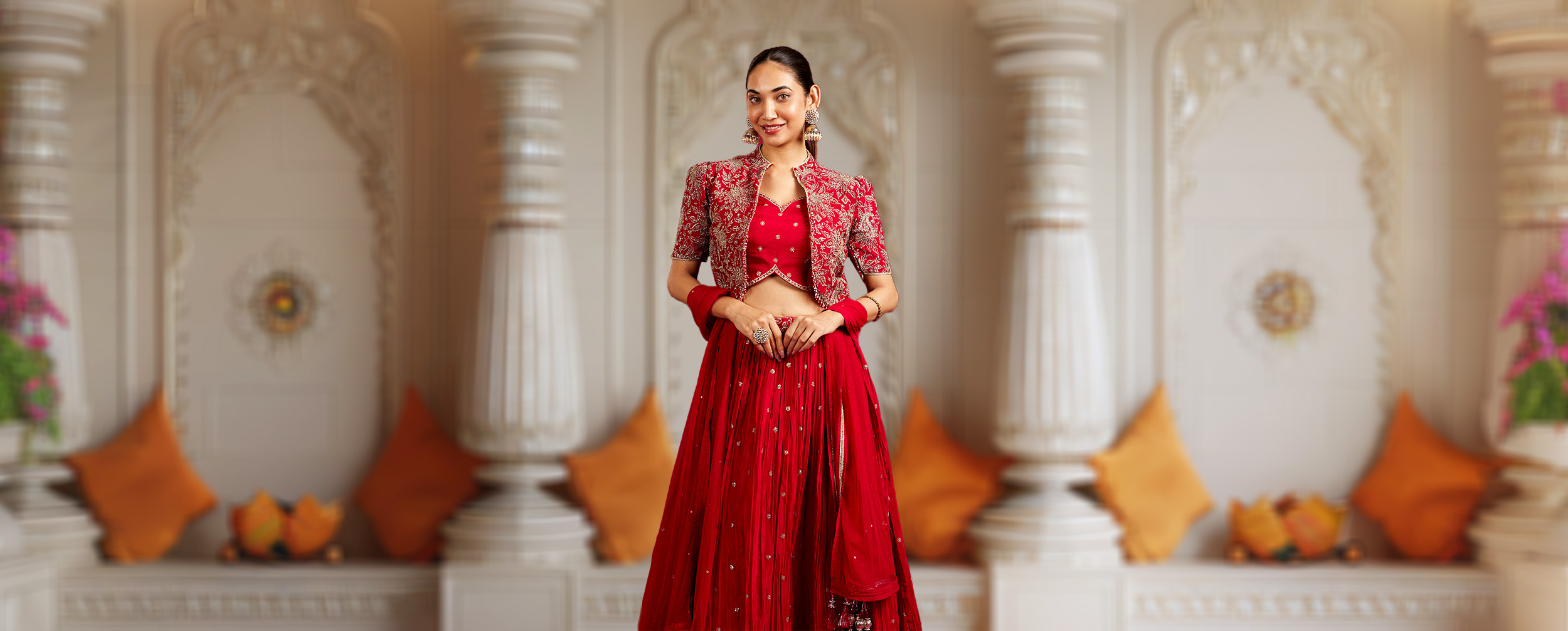 Woman in a red flared lehenga skirt and short embroidered jacket, suitable for a festive event.