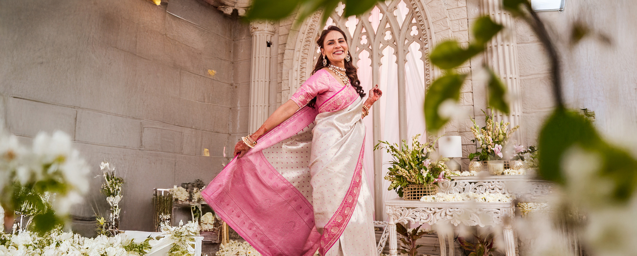 Mother in a pink saree styled for a Mother&rsquo;s Day ethnic wear celebration in an elegant floral setting.