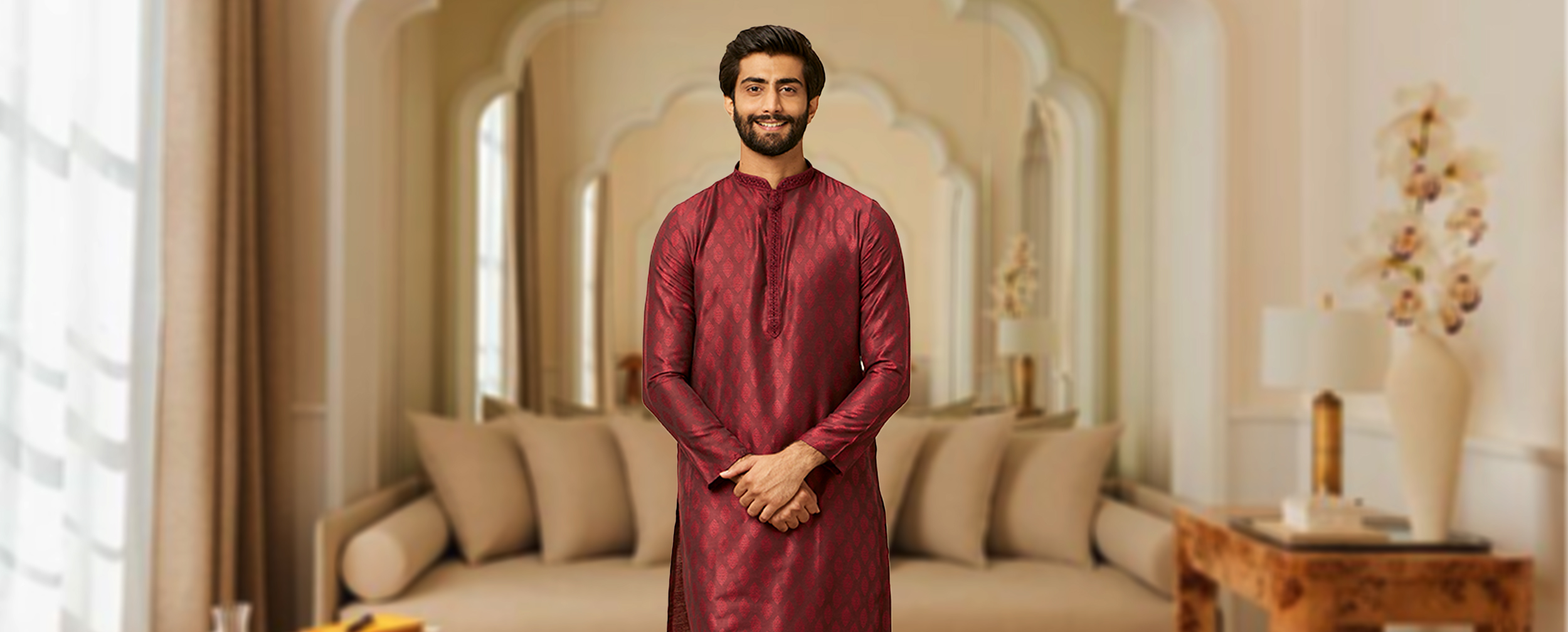 Man wearing a maroon silk A-line kurta with traditional design, styled elegantly for festive or wedding occasions in a royal indoor setting