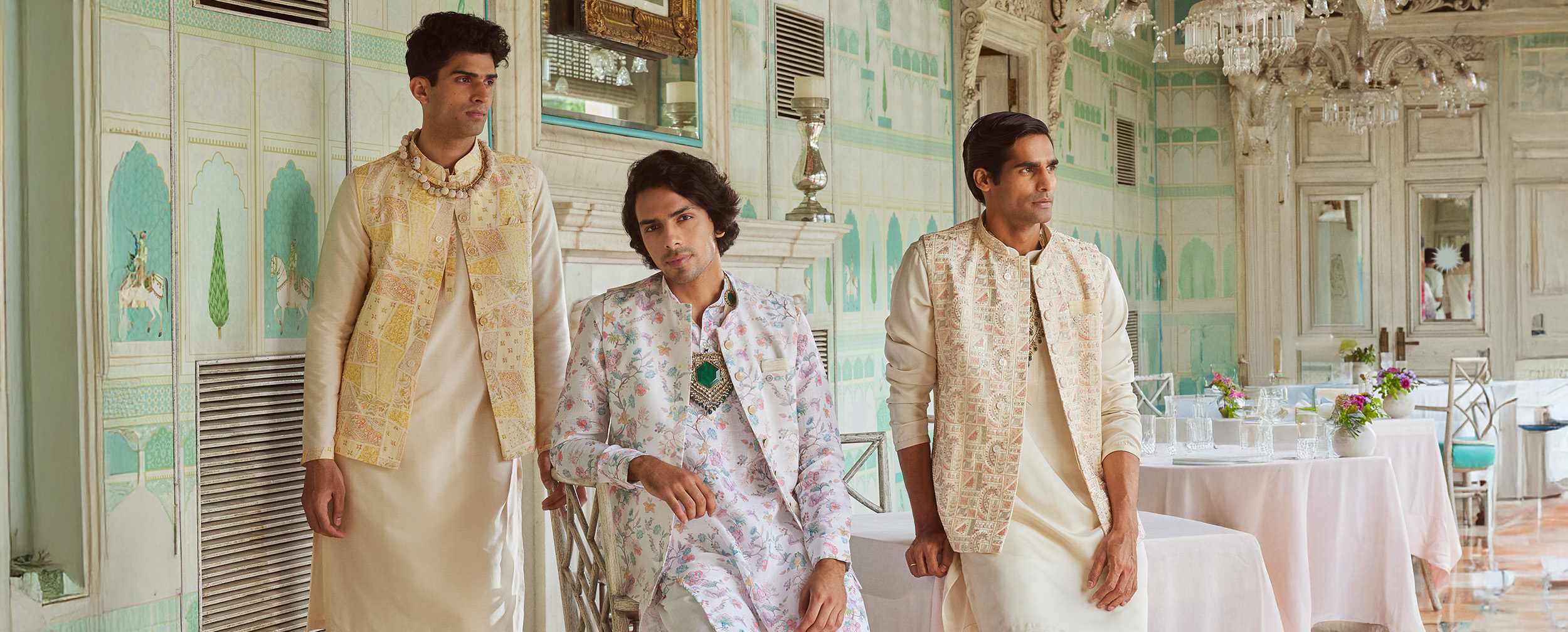 Three men in cream and off-white kurtas with patterned jackets, showcasing festive neutrals.  Three men in cream and off-white kurtas with patterned jackets, showcasing festive neutrals.