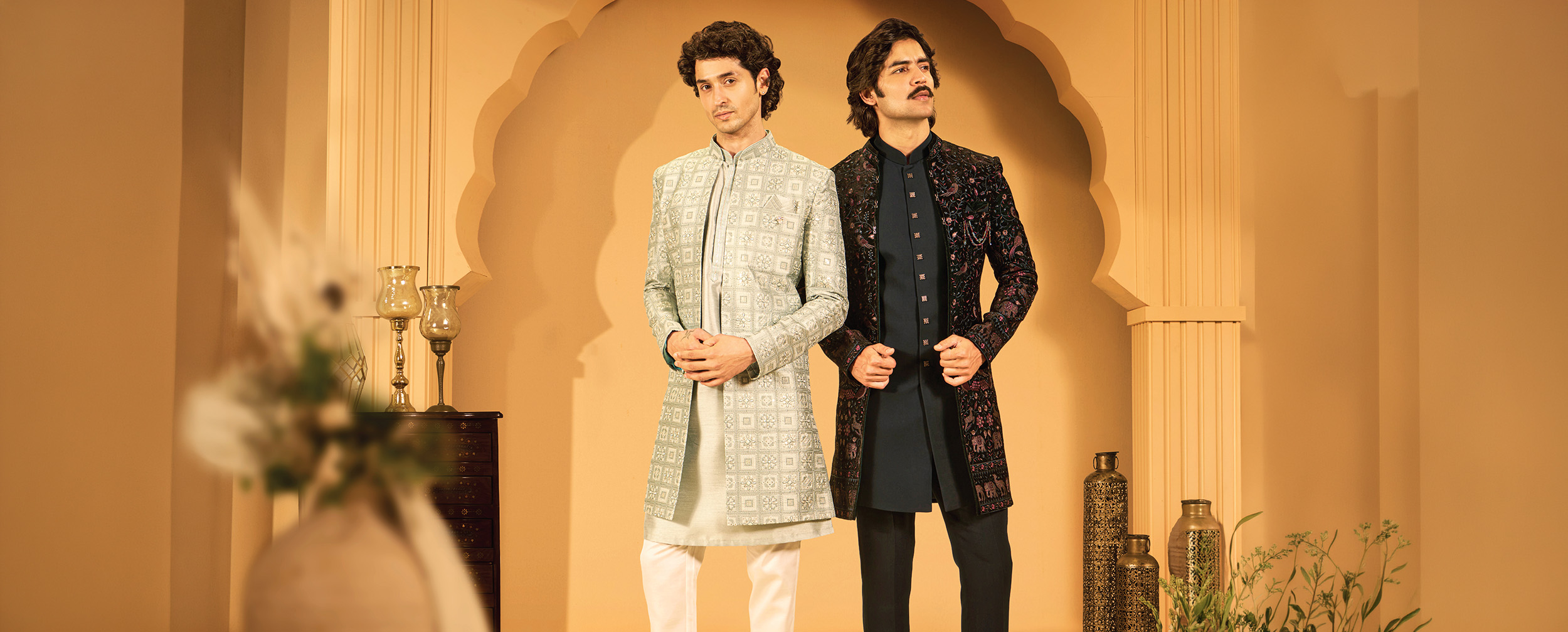 Two men wearing embroidered Jodhpuri wedding outfits in ivory and black
