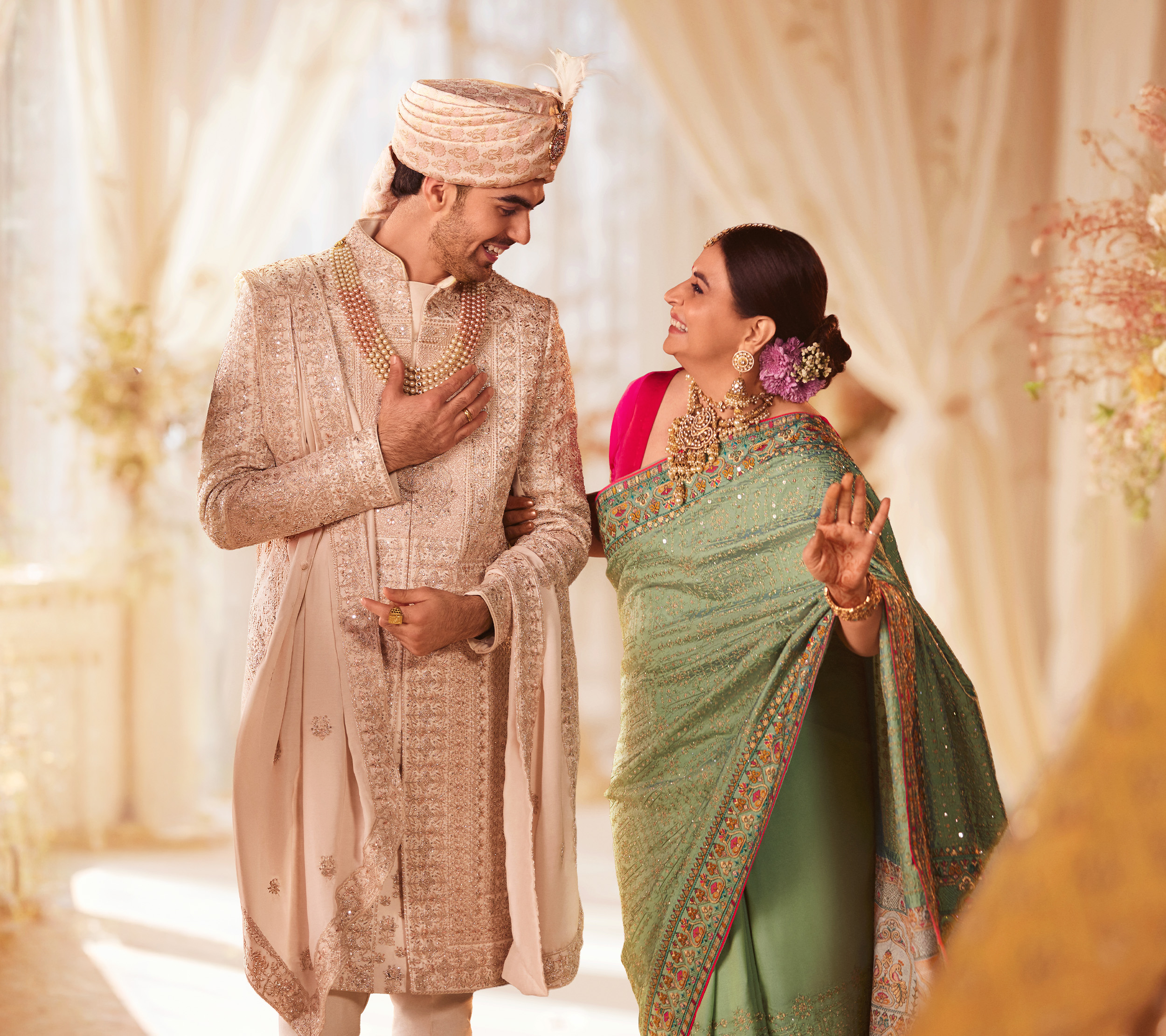 Mother in a green saree sharing a joyful Mother’s Day moment with her son dressed in traditional wedding attire.
